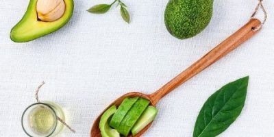Avocado essential oil, chunks, and fruits in white background